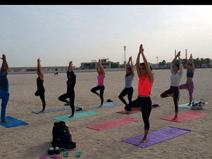 Group practising standing yoga poses at the beach