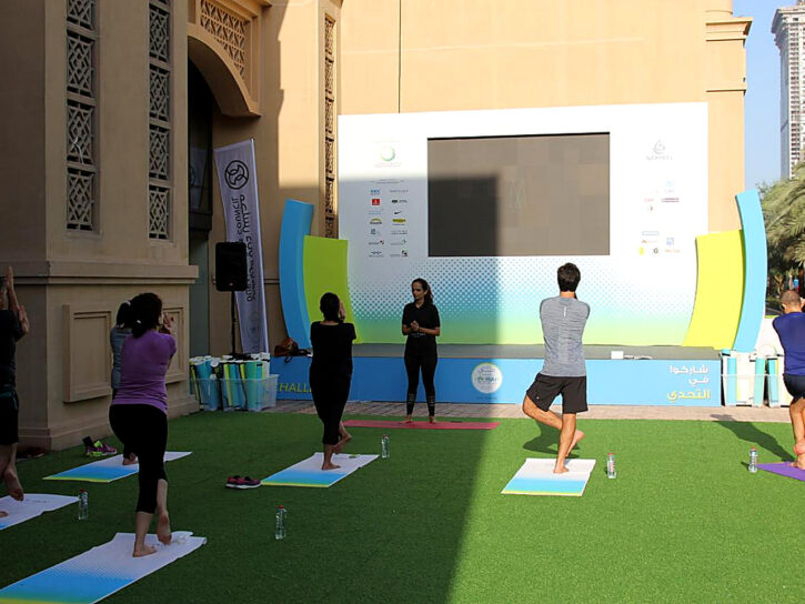 Group practising yoga on a green outdoor surface